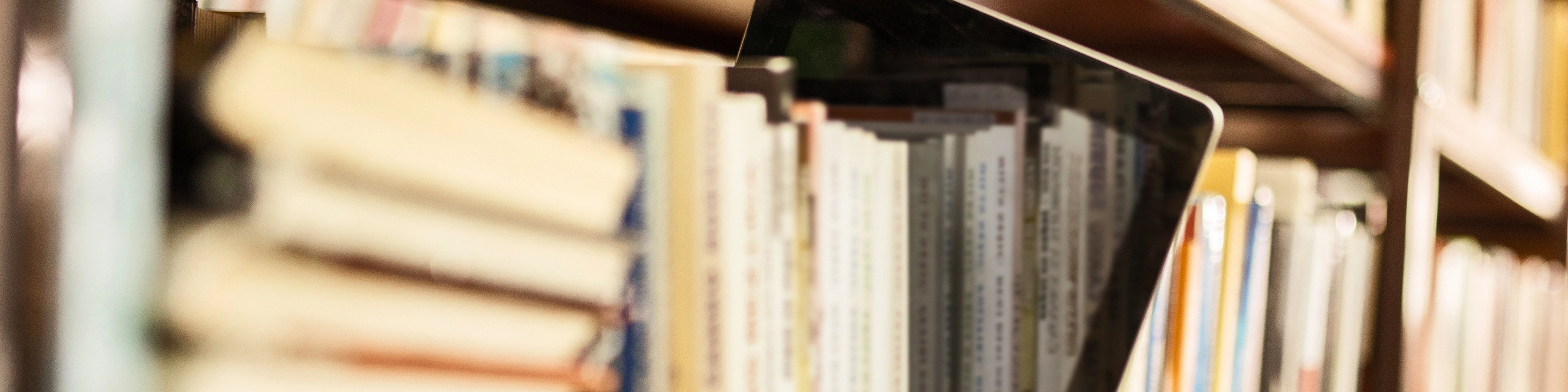 Tablet wciśnięty między ustawione na półce książki