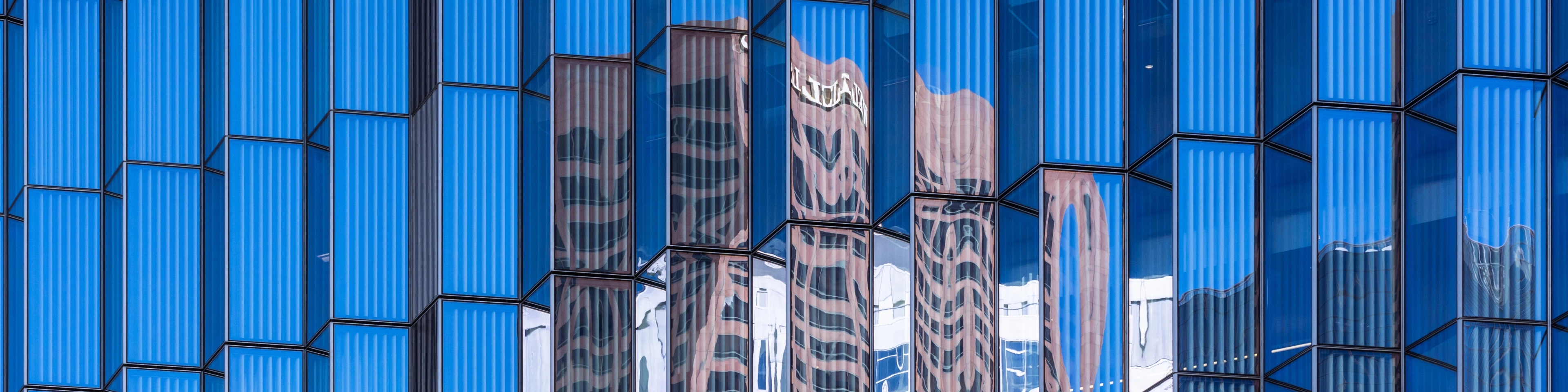 Fasada budynku odbijająca się w oknach wieżowca