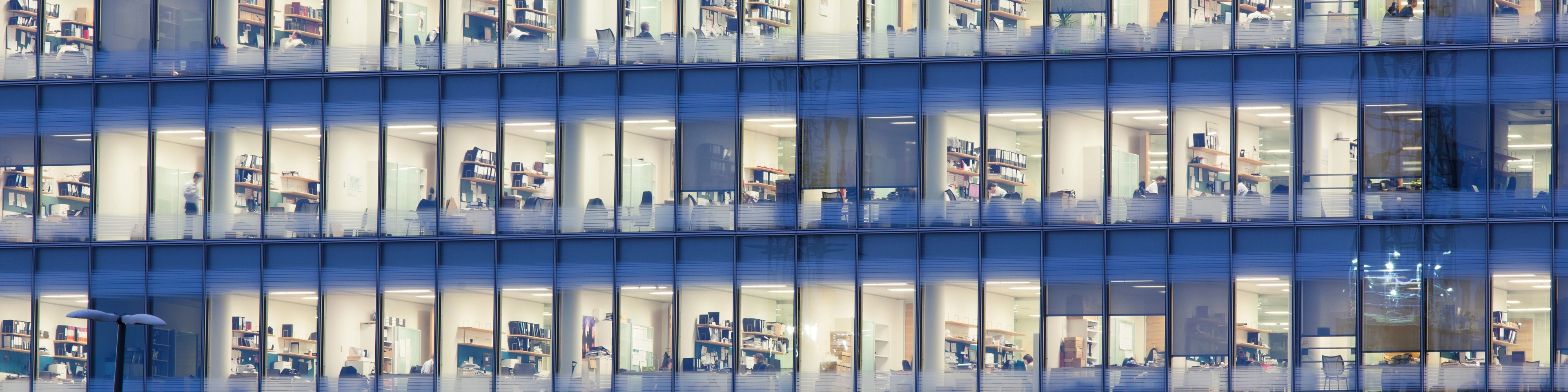 Fasada biurowca z biurkami i regałami widocznymi za szybami