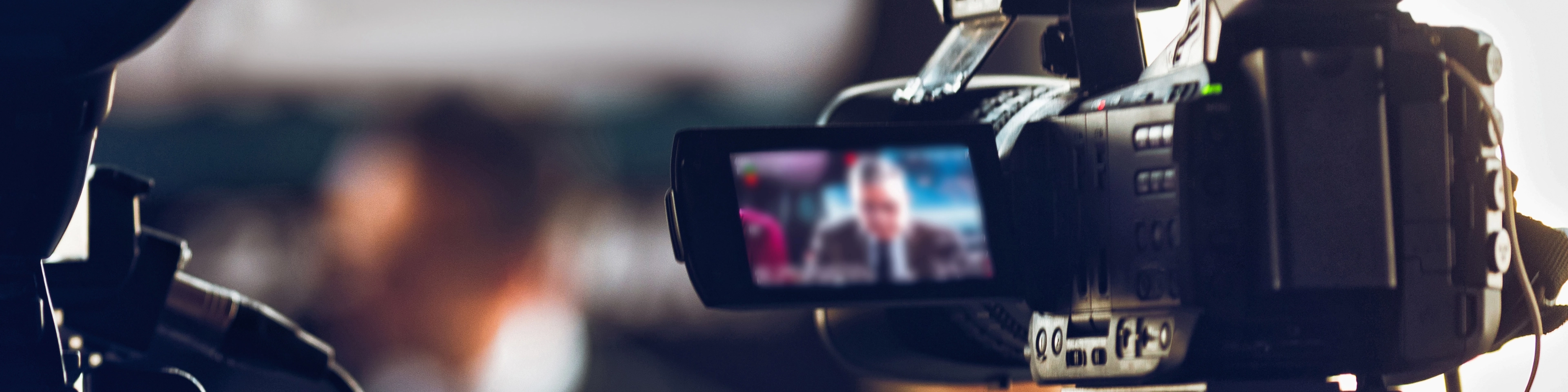 Kamera wideo nagrywająca osobę w garniturze