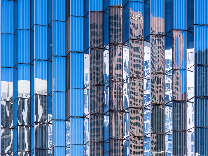 Fasada budynku odbijająca się w oknach wieżowca